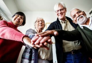 4 older people leaning in together